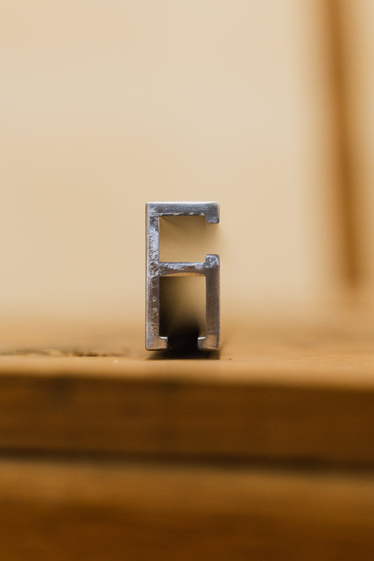 end view of A double track aluminum extrusion, typically used as a component in woodworking jigs or saw fences, silver in color available in several lengths.