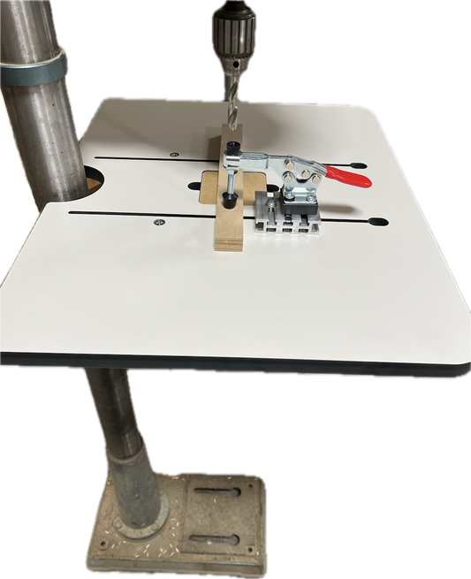 The image shows a Woodhaven 1828 Toggle Clamp attached to a drill press table, designed to hold workpieces in place for drilling.