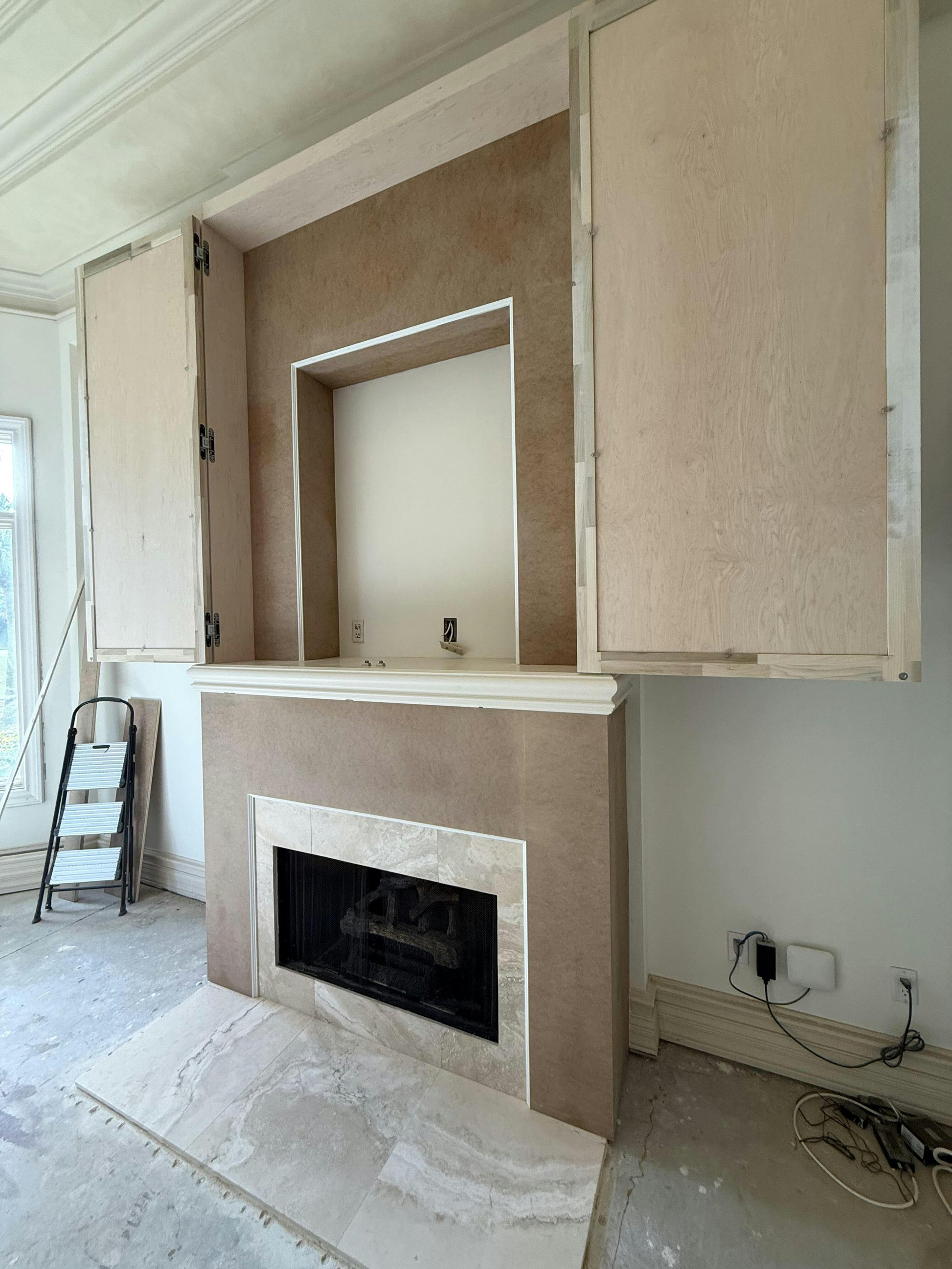 Unfinished room with a fireplace and cabinets under construction.