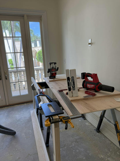 Woodworking setup with table saw, drill, and other tools on a workbench.