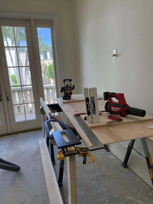 Woodworking setup with table saw, drill, and other tools on a workbench.