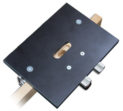 A black phenolic hinge template for routing the two-step mortises required for invisible hinges, showing two retractable stops and a central slot for a router bit.