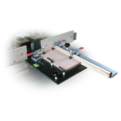 A Woodhaven large coping sled, primarily black in color, with clamps and adjustable feed handles, designed for making precise cuts on a router table or shaper.