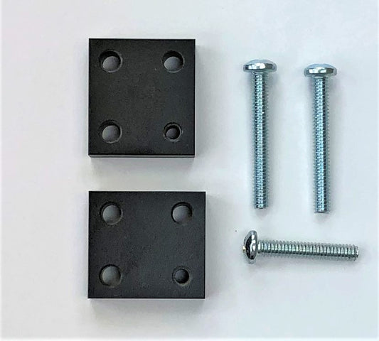 Two black metal riser blocks with four holes each and four silver screws laid out on a white surface.